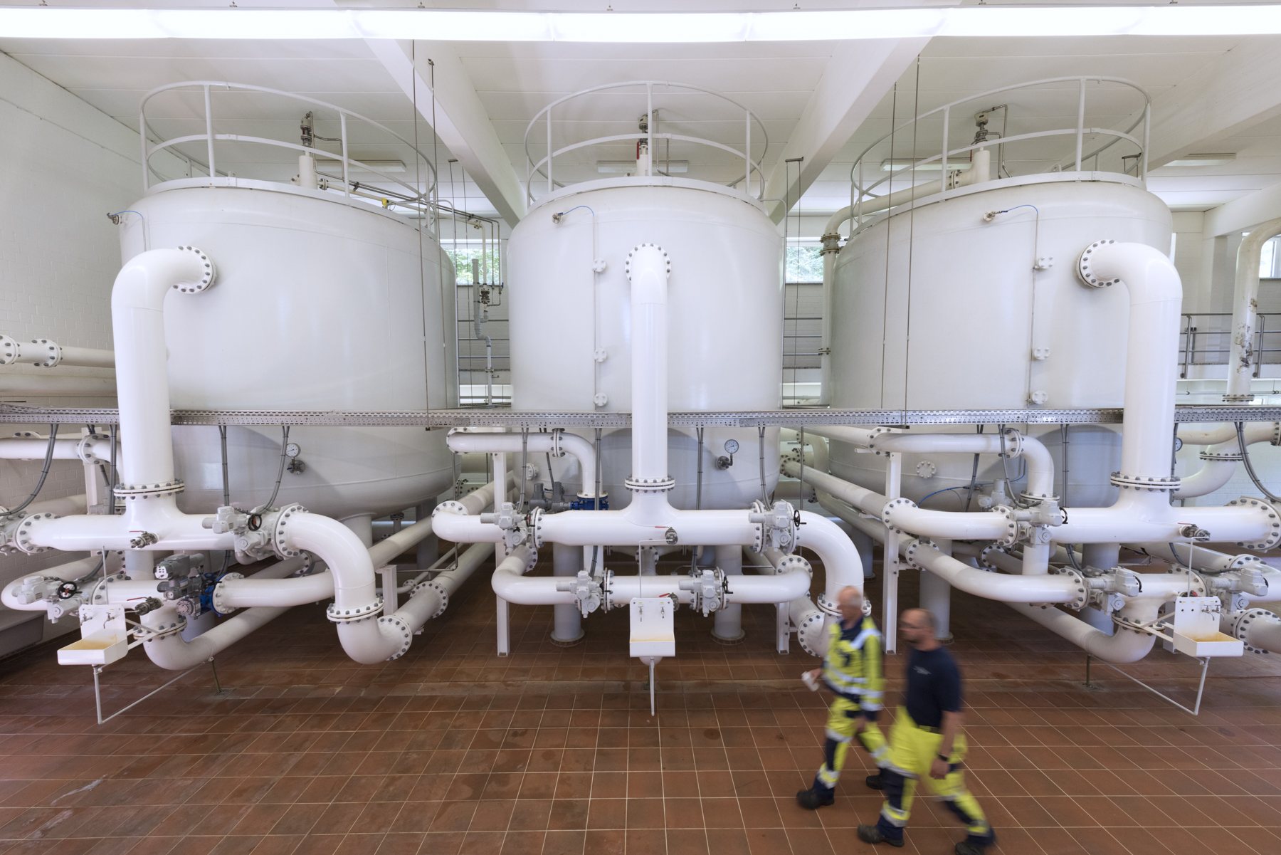 Blick ins Innere des Wasserwerkes Mitarbeiter gehen vor großen Kesseln im Wasserwerk Wittkoppenberg entlang.